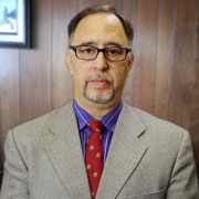 Serious older man with salt-and-pepper hair and facial hair